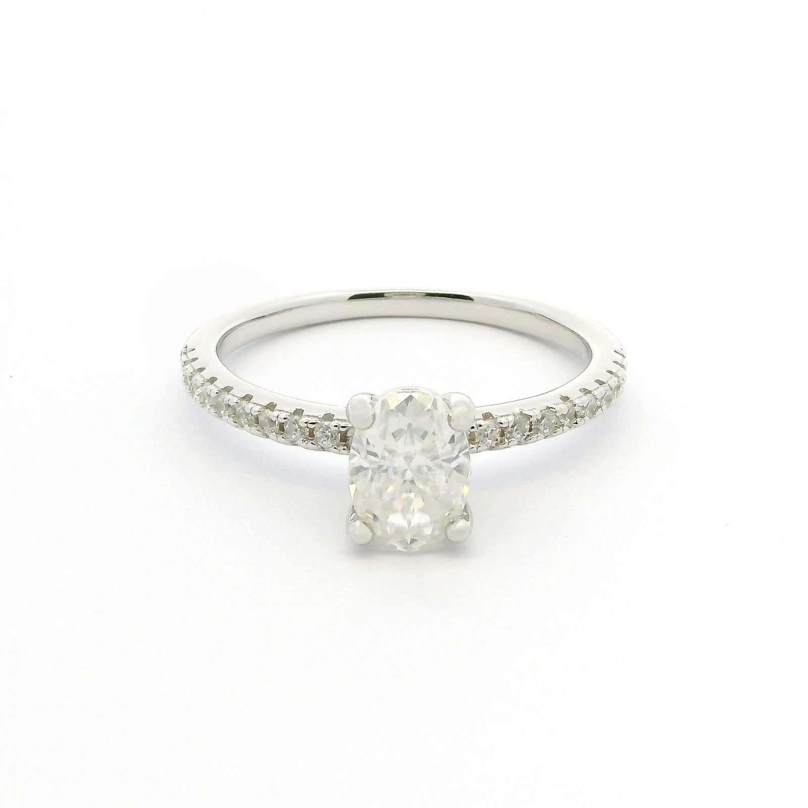 A silver solitaire engagement ring featuring a round brilliant-cut center stone and a pavé-set band, shown on a plain white background.