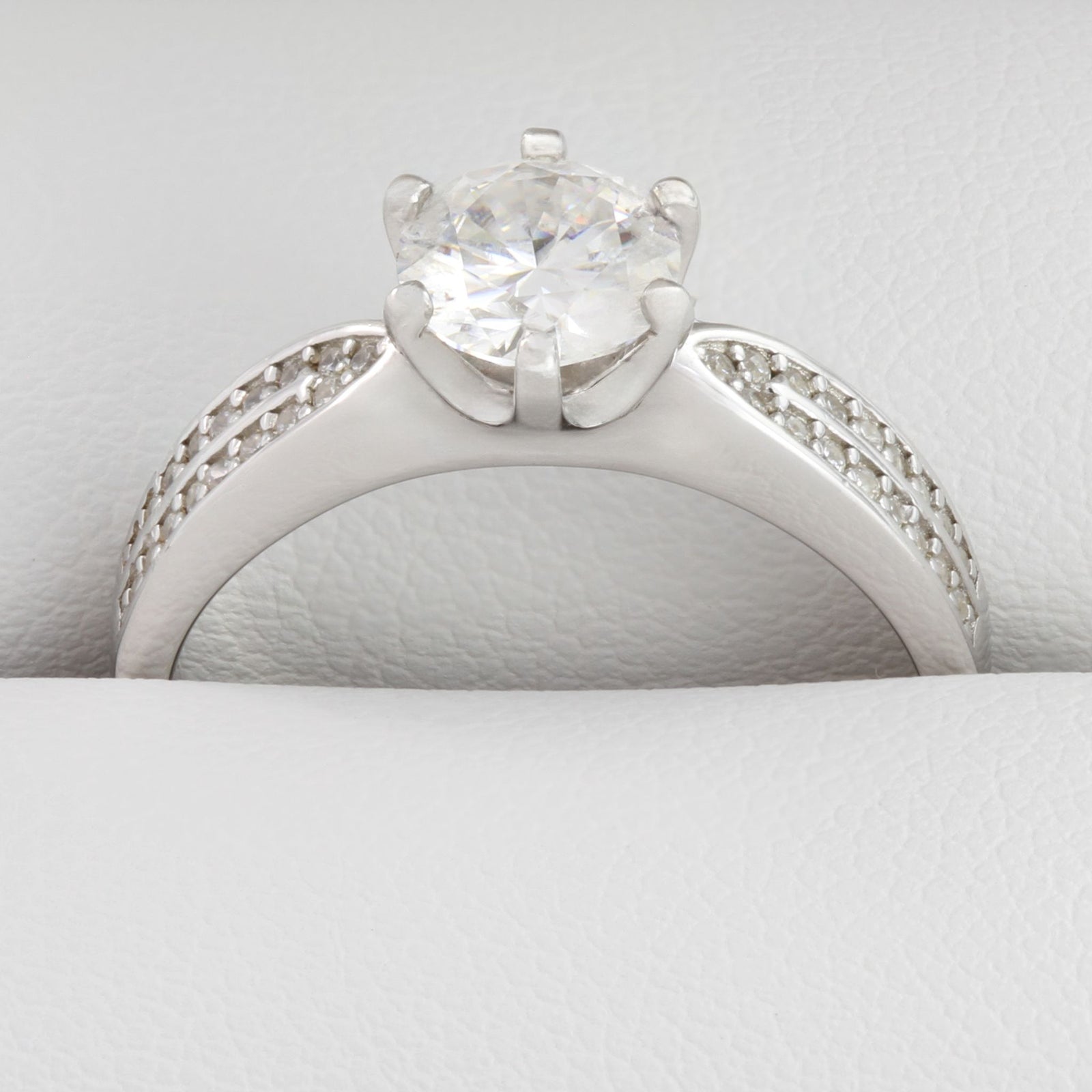 Close-up of round moissanite stones in white gold wide band ring