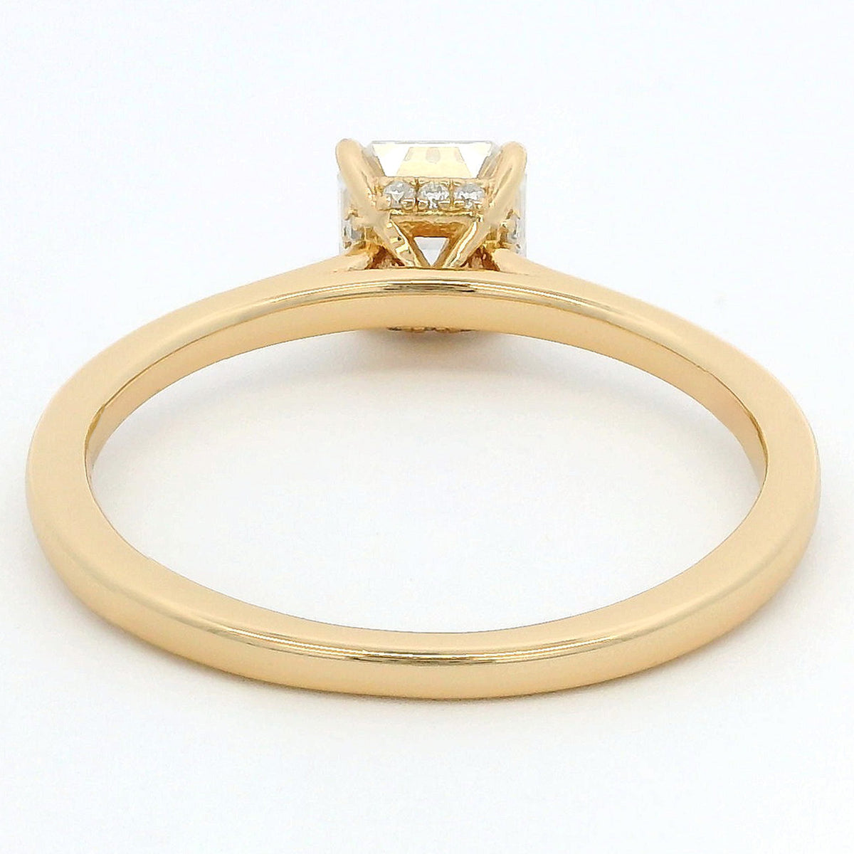 A yellow gold ring with a square-cut diamond center stone and small side diamonds, shown from a top-down view on a white background.
