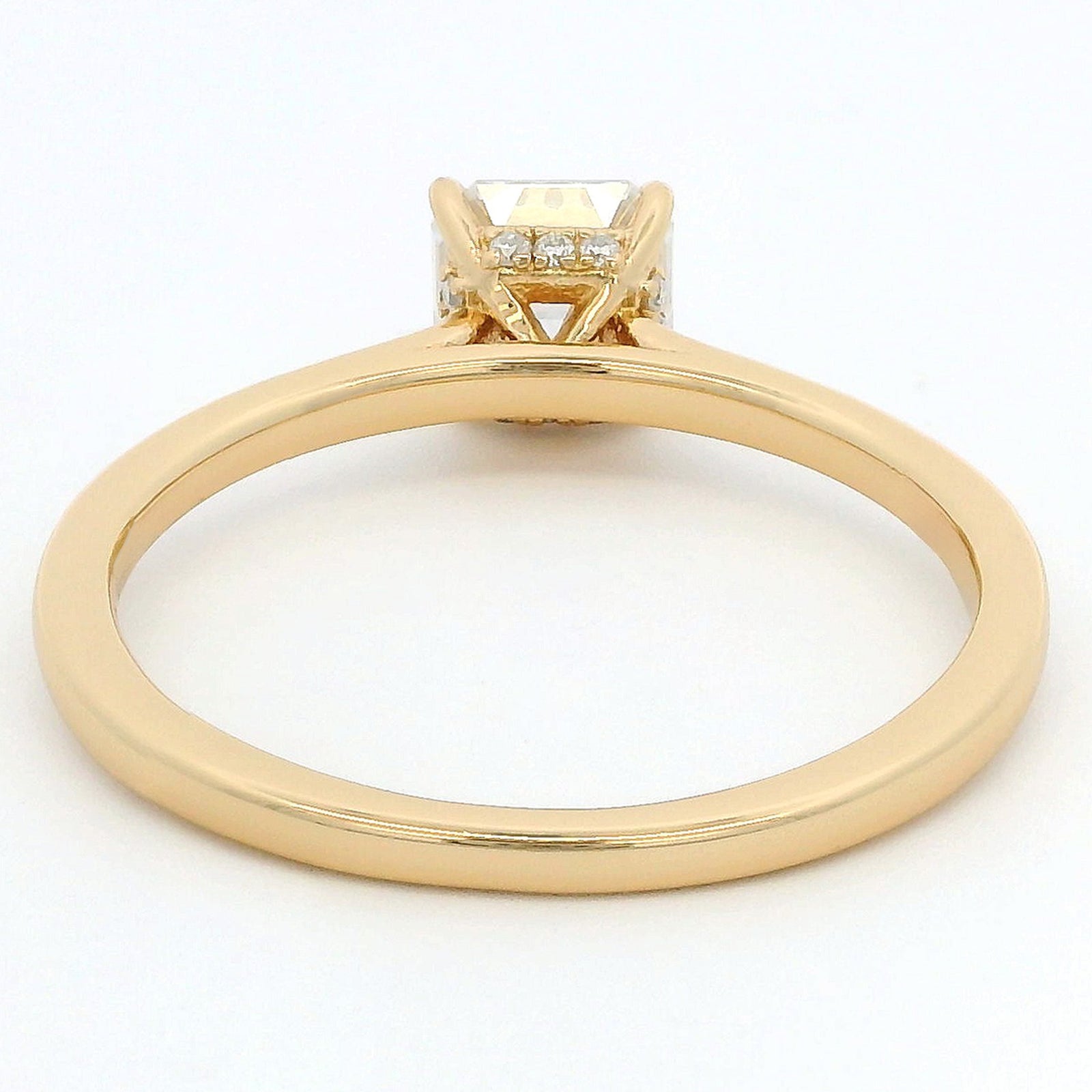 A yellow gold ring with a square-cut diamond center stone and small side diamonds, shown from a top-down view on a white background.