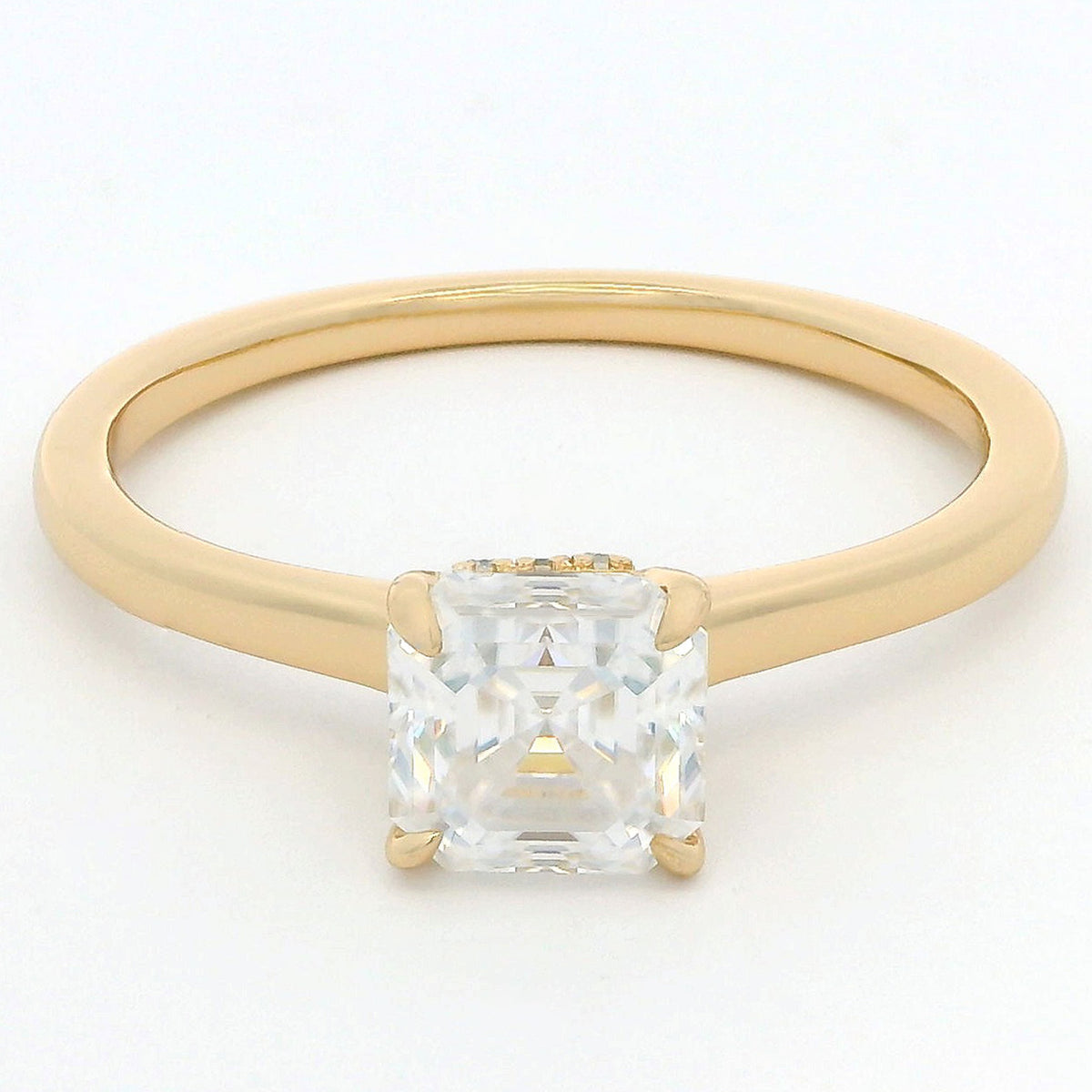 A yellow gold solitaire ring featuring a large, clear, square-cut gemstone in a four-prong setting, shown against a plain white background.