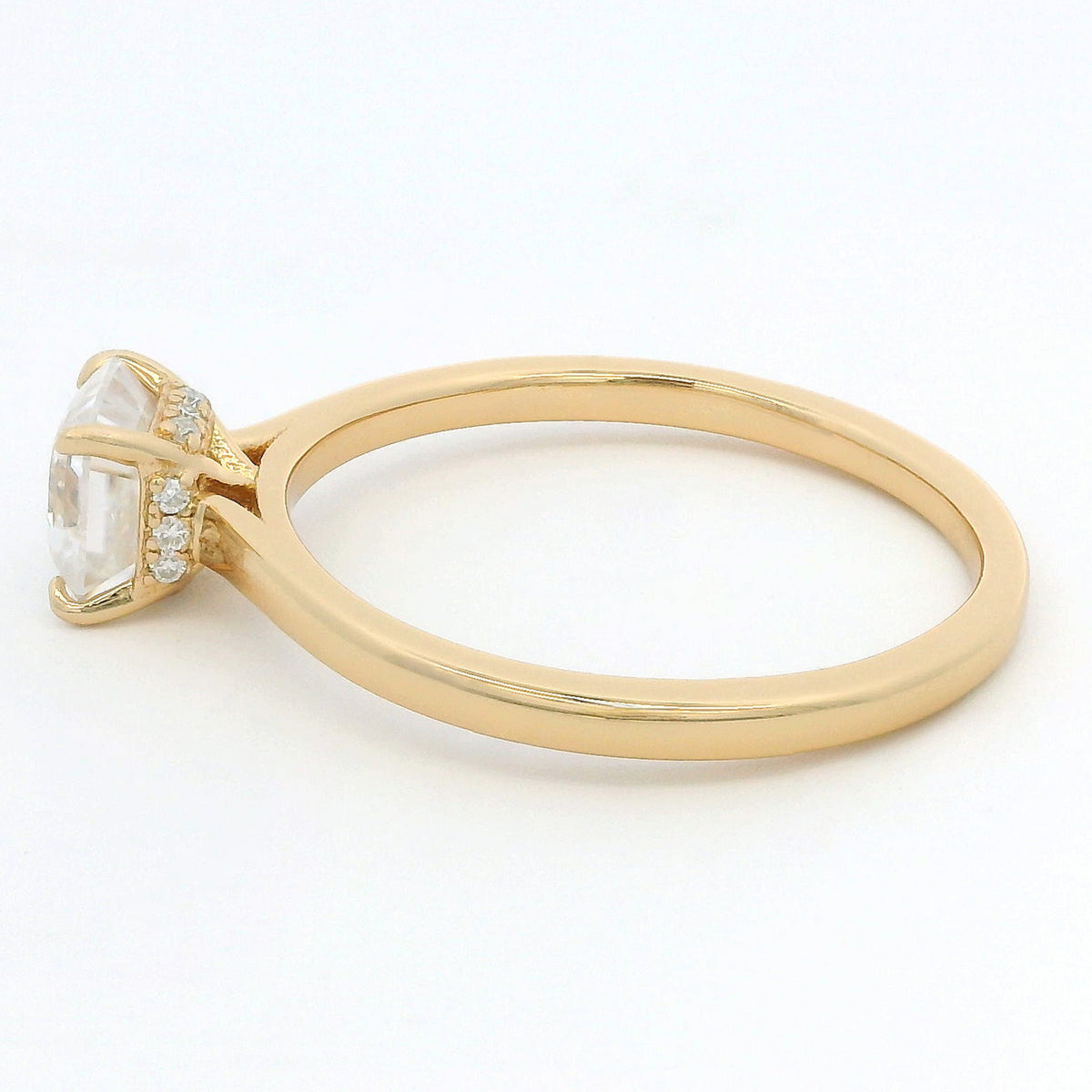 A yellow gold ring featuring a large clear rectangular gemstone in a prong setting with small accent diamonds along the band, shown on a clean white background.
