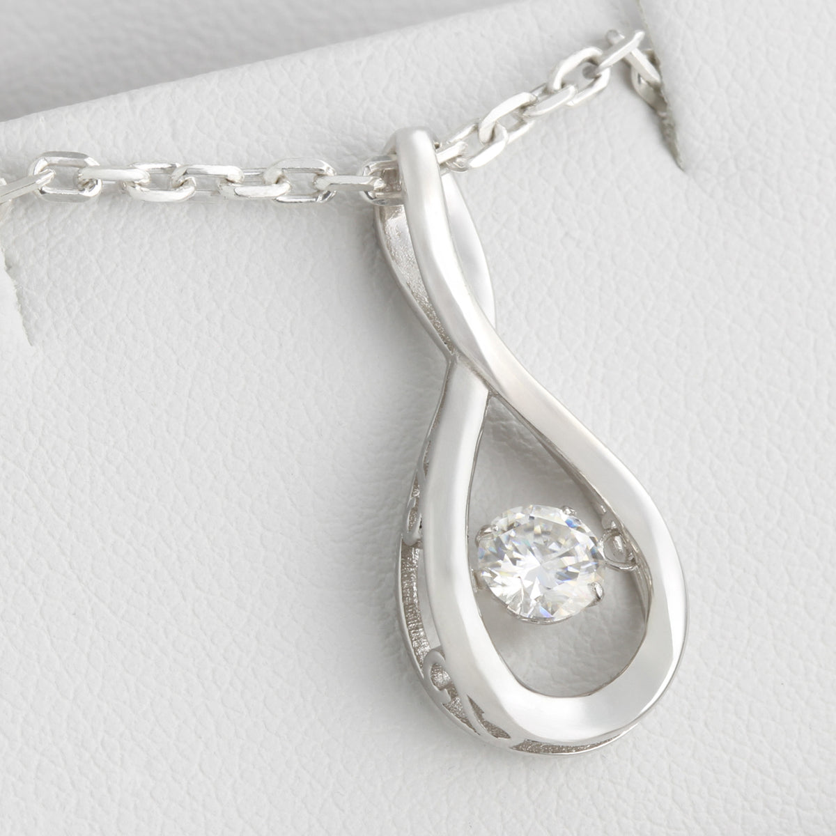 Close-up of white gold infinity moissanite pendant necklace displayed in gift box