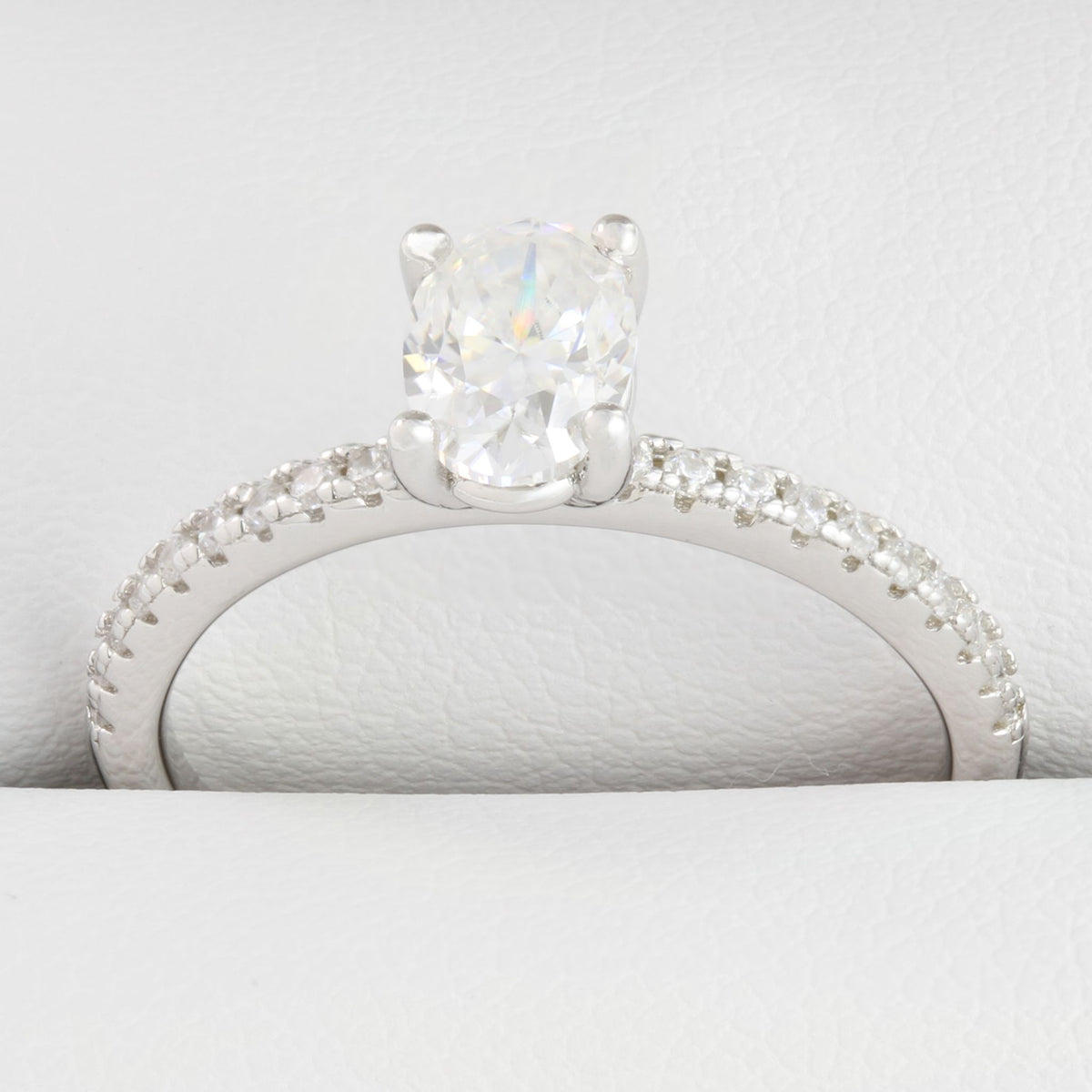 Close-up of oval-shaped moissanite centre stone with small round stones in white gold ring