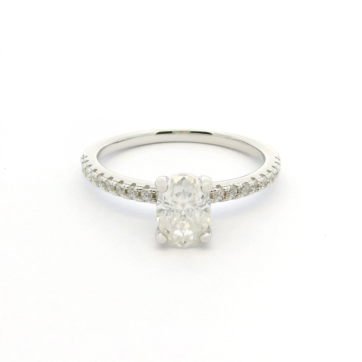 A silver solitaire engagement ring featuring a round brilliant-cut center stone and a pavé-set band, shown on a plain white background.