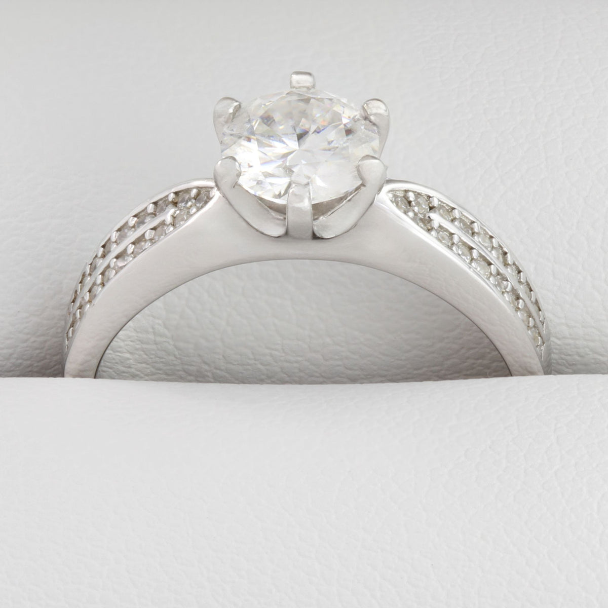 Close-up of round moissanite stones in white gold wide band ring